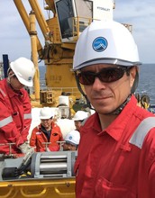 Researchers wearing hardhats on ship.